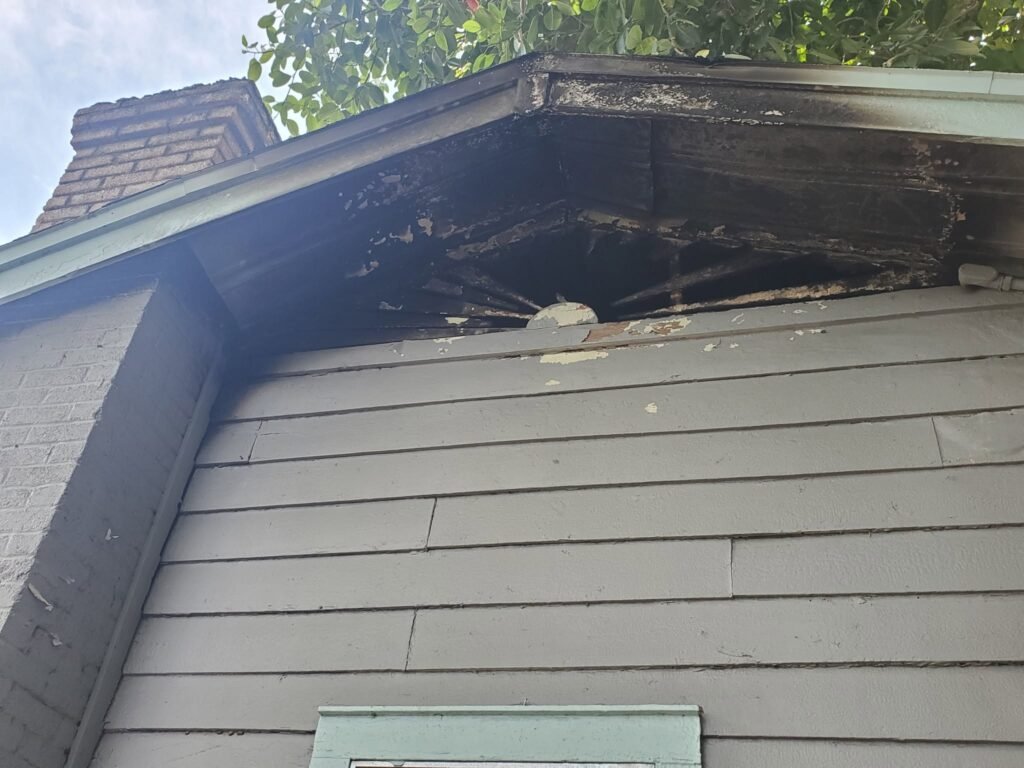 Exterior fire damage to roof soffit and fascia — before restoration